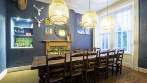 Comedor con una larga mesa de madera, seis sillas y tres lámparas colgantes.