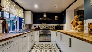 Una cocina moderna con armarios blancos, un horno de acero inoxidable y un suelo de baldosas estampadas.