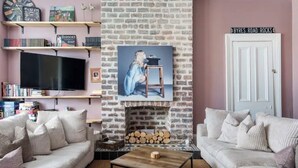 Una sala de estar con chimenea de ladrillo, televisor y estantería.