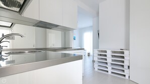 A modern kitchen with a stainless steel sink, white cabinetry, and a built-in oven. - Rivazzurra Homes - 13 (Termoli)