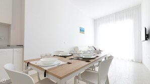 A modern dining area with a wooden table, white chairs, and a white wall. - Rivazzurra Homes - 20 (Termoli)