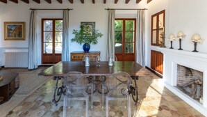 A dining area with a wooden table, chairs, a vase, and a fireplace. - TRADITIONAL  HOUSE. IDEAL FOR FAMILY. PRIVATE  POOL. WIFI WITH FIBER. A/C (Deià)