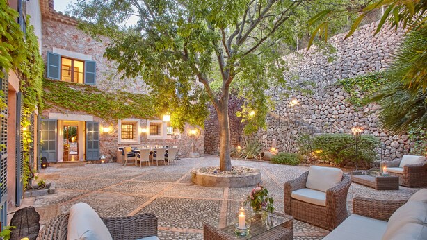 An outdoor patio with wicker furniture, a stone wall, and a tree providing shade. - TRADITIONAL  HOUSE. IDEAL FOR FAMILY. PRIVATE  POOL. WIFI WITH FIBER. A/C (Deià)