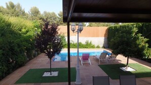 A covered outdoor area with a swimming pool, patio furniture, and a pergola.