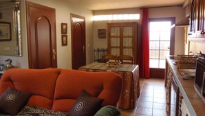 A living room with a sofa, a dining table, and a kitchen area with a microwave.