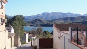 A narrow street leading to a body of water with mountains in the background.