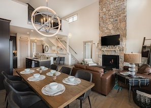 A spacious living area with a stone fireplace, a dining table set for four, and a comfortable seating area. - Lone Eagle Chalet at Granby Ranch - With Hot Tub! (Granby)
