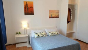 A bedroom with a bed, nightstands, a lamp, and two paintings on the wall.