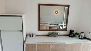 A kitchenette with a built-in oven, a coffee maker, and a small plant on the counter.