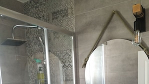 A bathroom with a glass-enclosed shower, a white sink, and a round mirror. - Balcón a la Bahía. Bay Views (Santander)