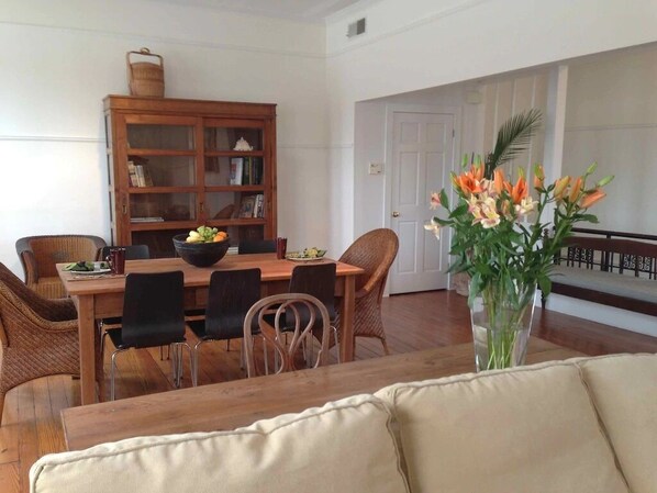 Un comedor con mesa de madera, sillas y una estantería.