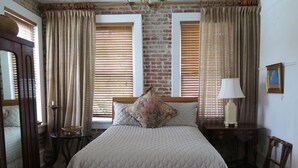 A bedroom with a large bed, a bench, a table, and a lamp.