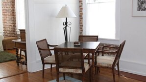 A dining area with a wooden table and wicker chairs, a floor lamp, and a patterned rug.