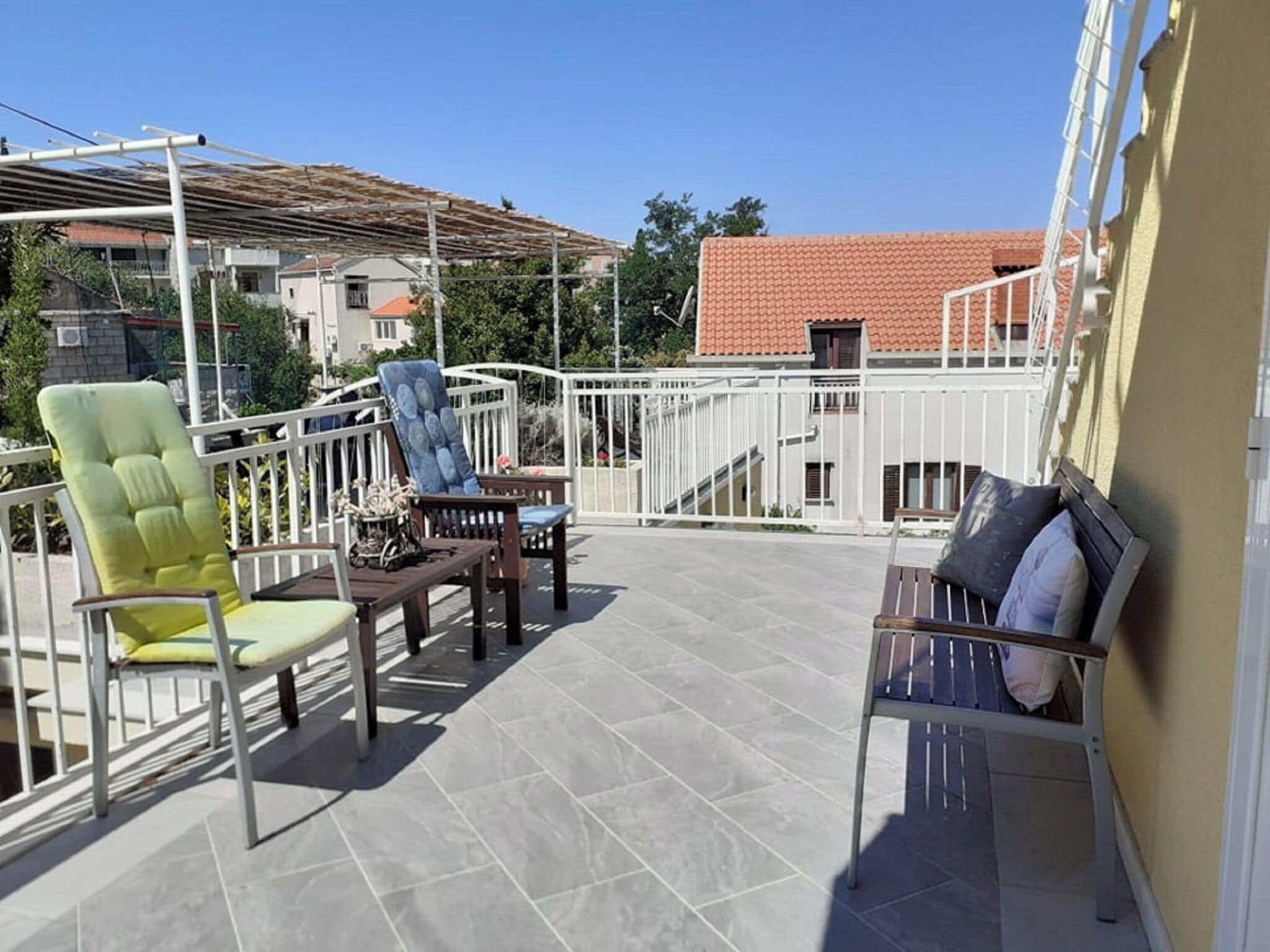 An outdoor patio with a pergola, a wooden table, and two chairs.