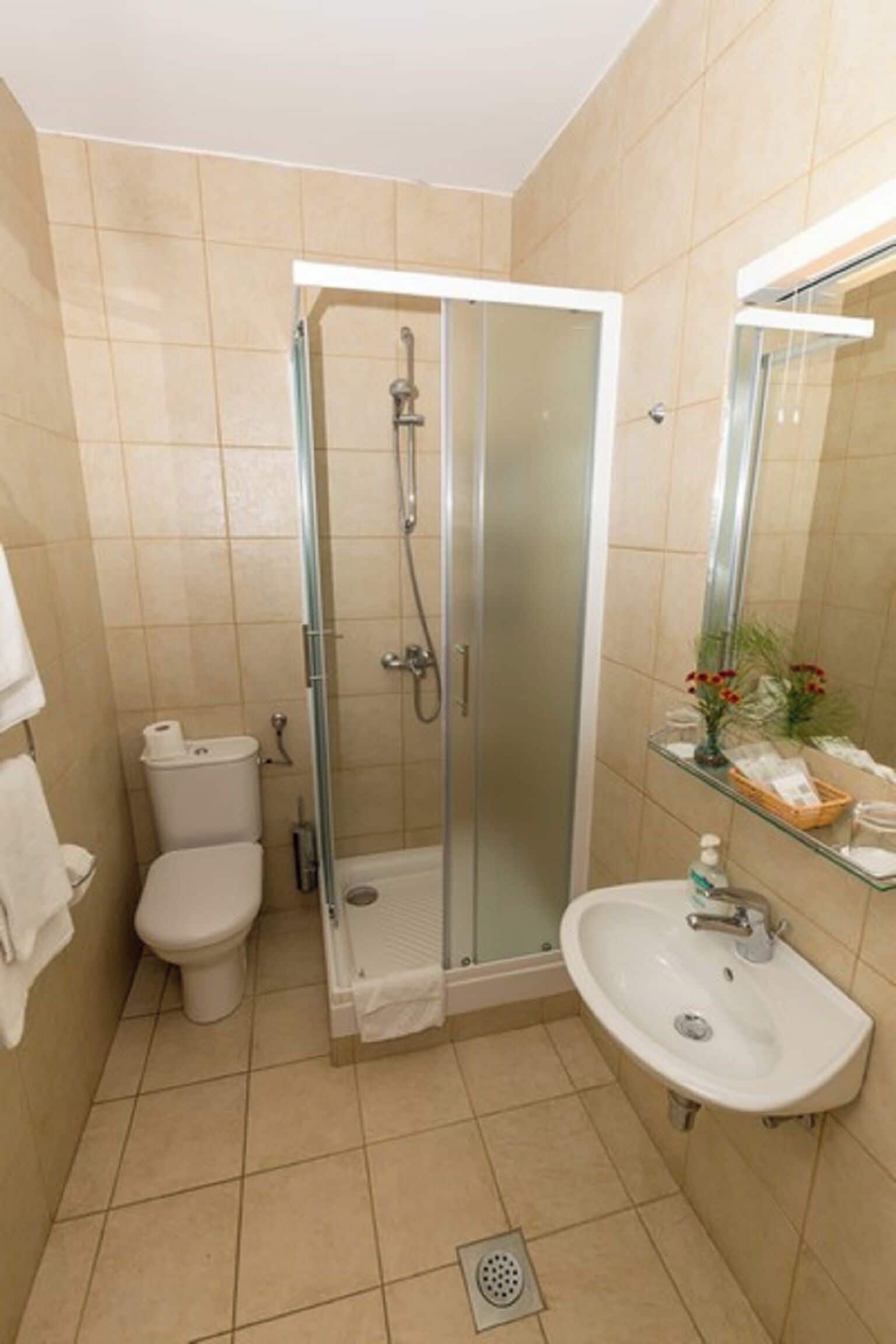 Un baño con ducha de vidrio, inodoro, lavabo y espejo.