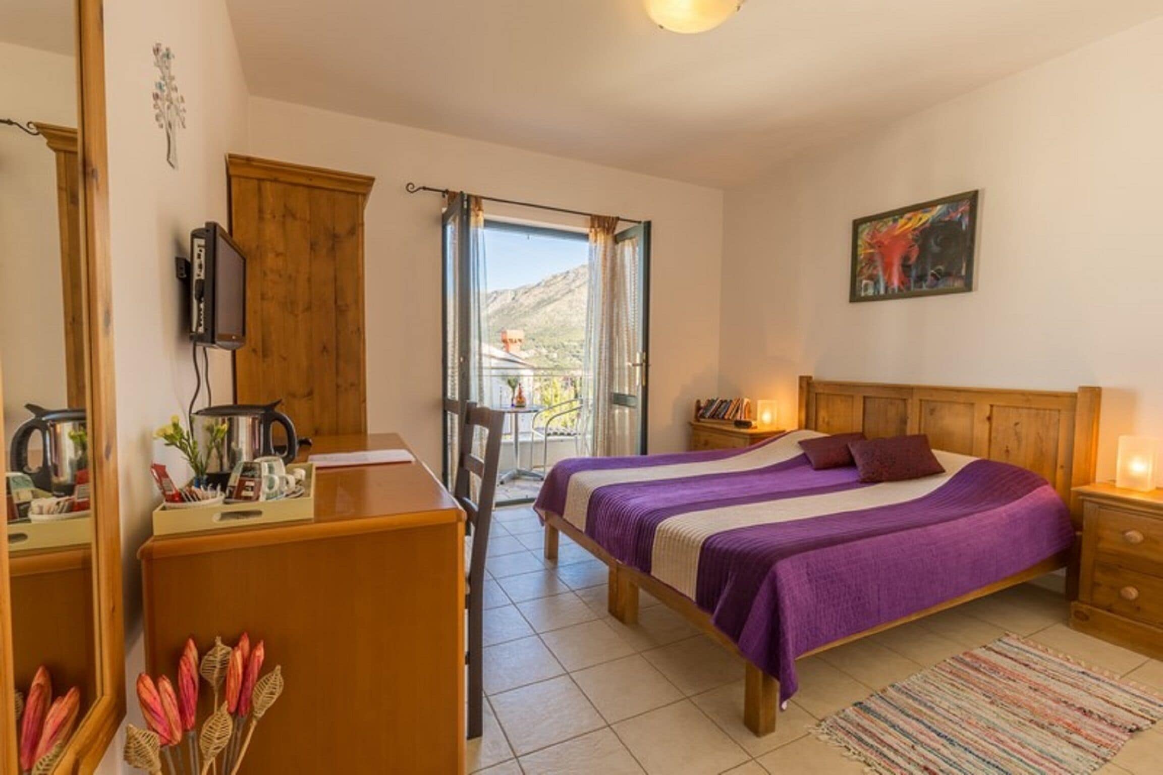 Une chambre à coucher comprenant un lit, un bureau, une chaise, un téléviseur et une fenêtre donnant sur les montagnes.