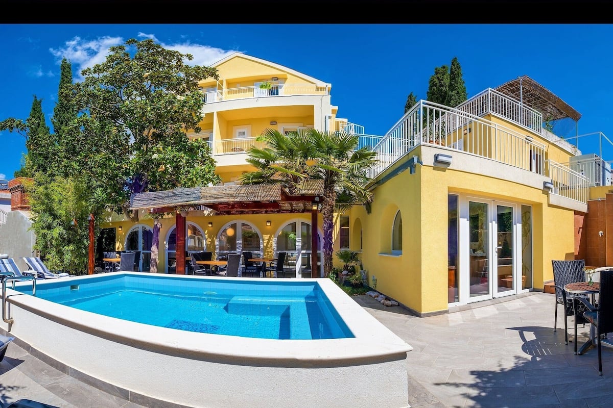 A two-story building with a pool, outdoor seating, and a covered patio area.