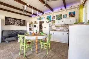 A kitchen with white cabinets, a dining table with chairs, and a refrigerator.