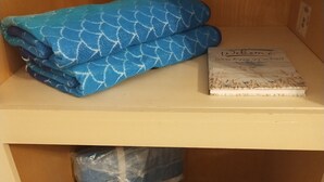 A shelf with folded blue towels, a welcome sign, a blue bag, and a patterned bag. - Country setting only 10 minutes to  Downtown. (Naples)