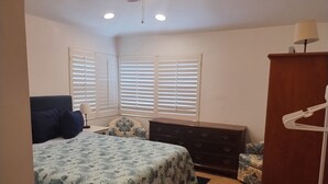A bedroom with a bed, dresser, chair, and a wardrobe. - Country setting only 10 minutes to  Downtown. (Naples)