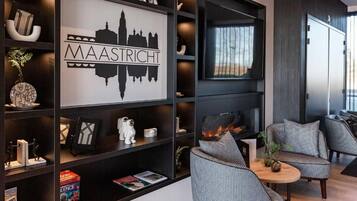 A modern living room with a fireplace, a bookshelf with various decorative items, and a seating area with patterned chairs.