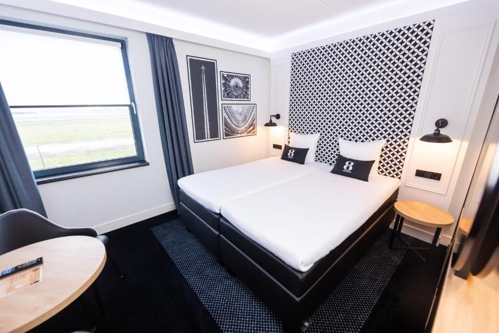 Habitación de hotel con cama, escritorio, silla, ventana y pared con diseño.