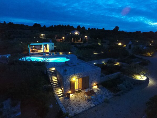 A nighttime view of a property with a swimming pool, stone buildings, and outdoor lighting. - Hacienda LUCIO/secluded estate/practice golf/enjoy the view and great pool (Grohote,Otok Šolta)