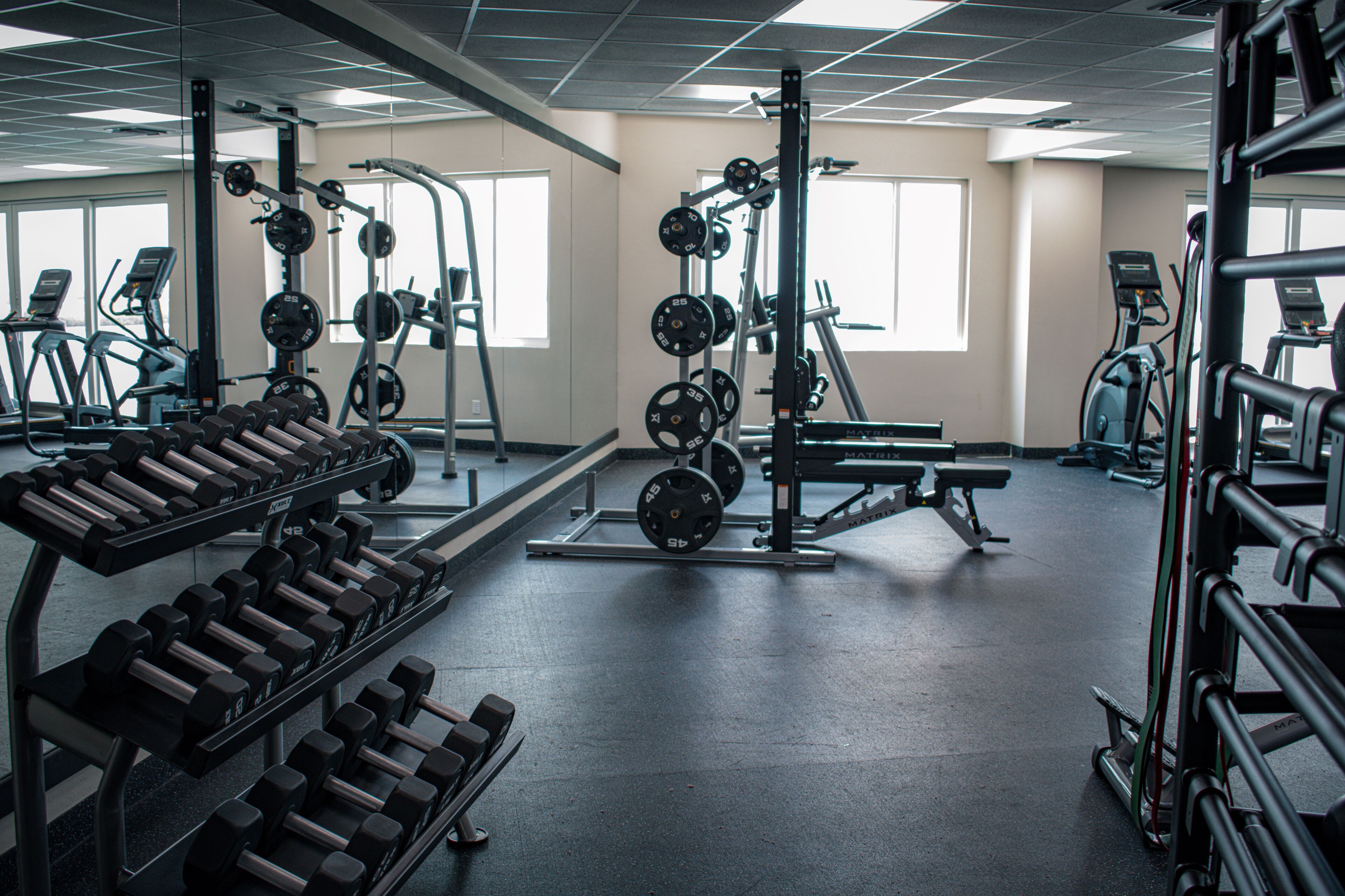 Une salle de sport équipée de matériel de musculation, de tapis de course et de vélos d’exercice.