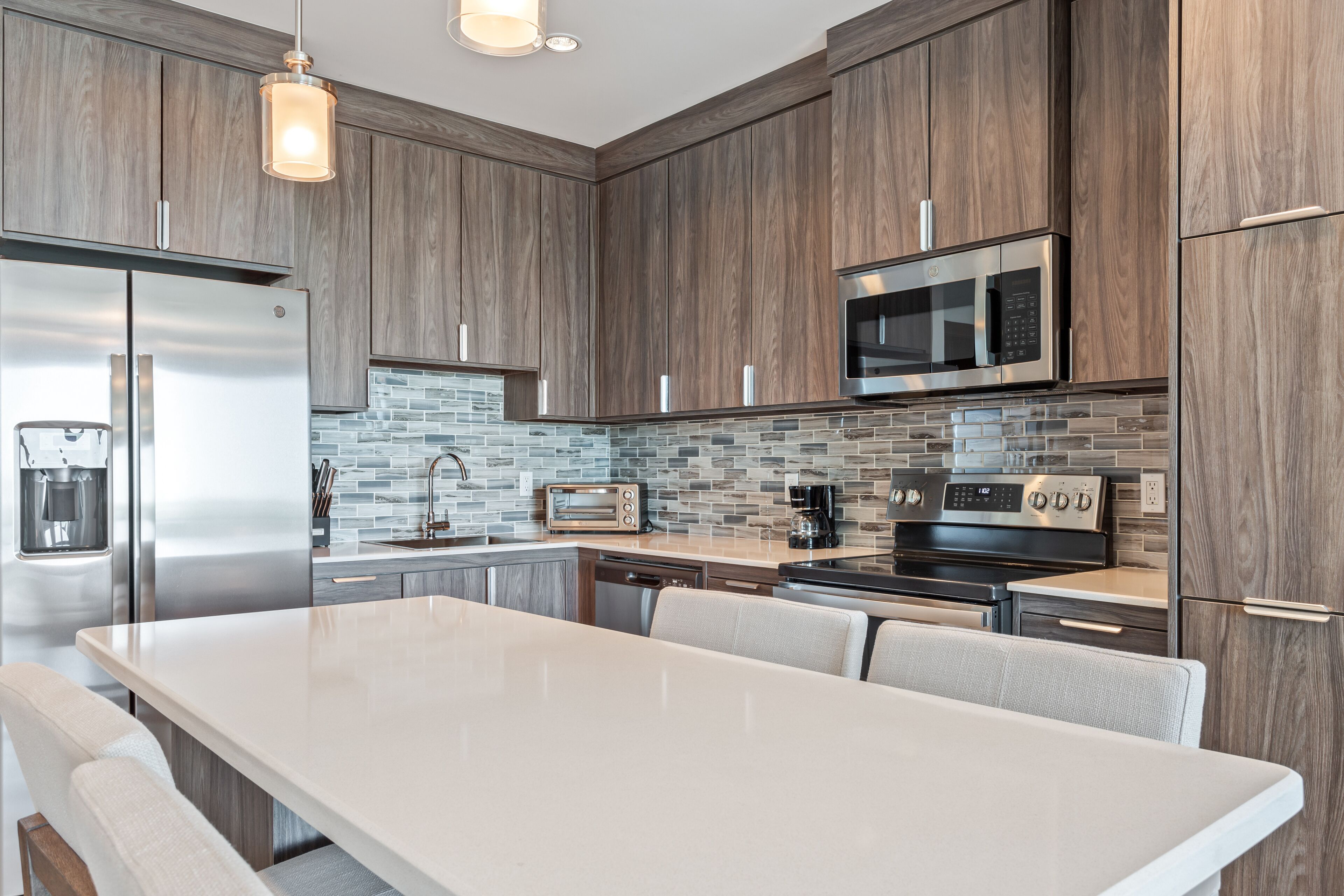 A modern kitchen with a large island, stainless steel appliances, and a stone backsplash.