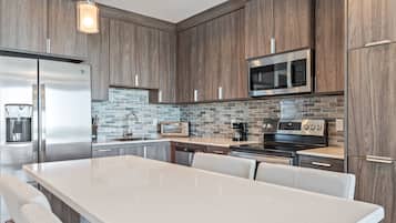 A modern kitchen with a large island, stainless steel appliances, and a stone backsplash.