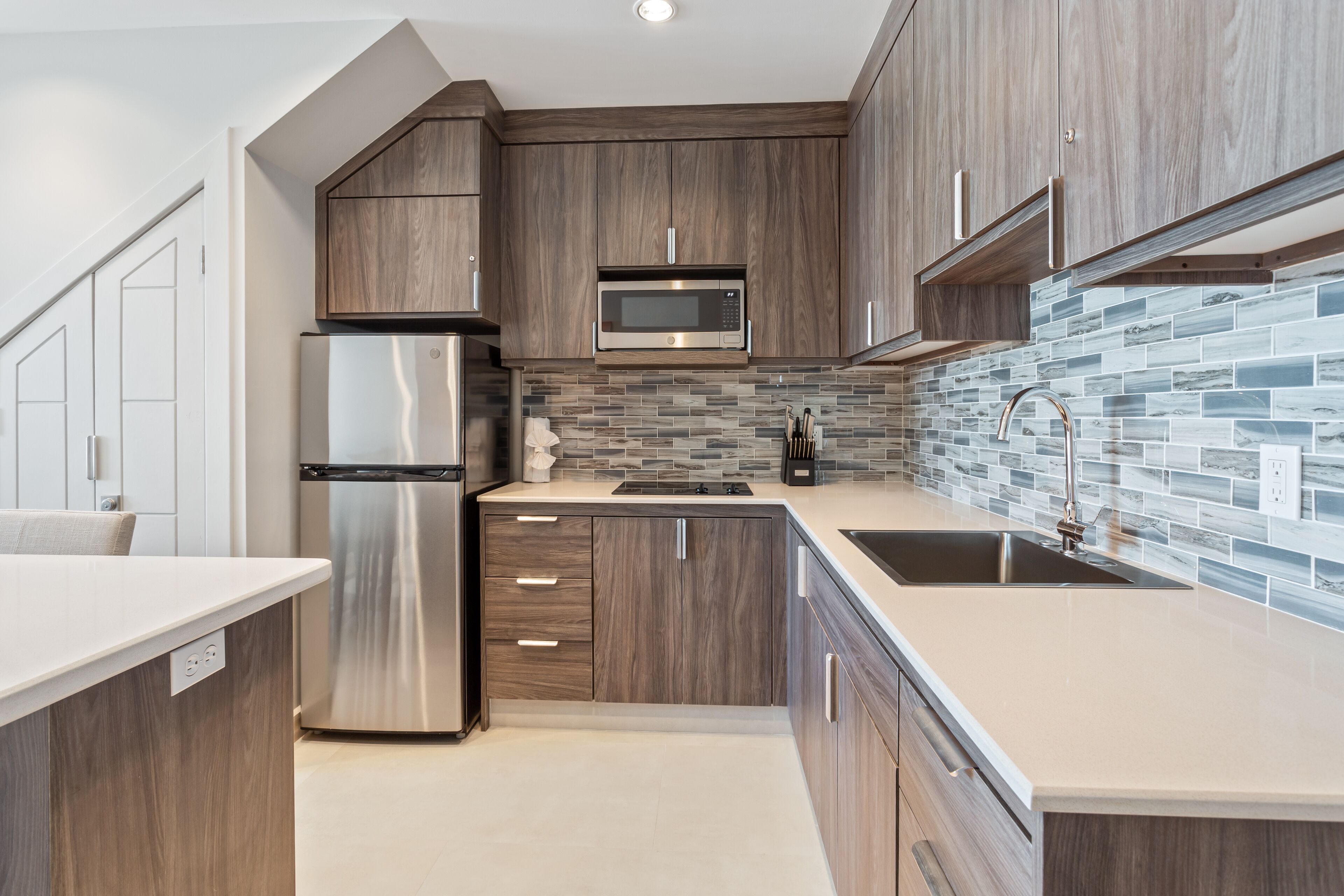 A modern kitchen with wooden cabinets, stainless steel appliances, and a tiled backsplash.