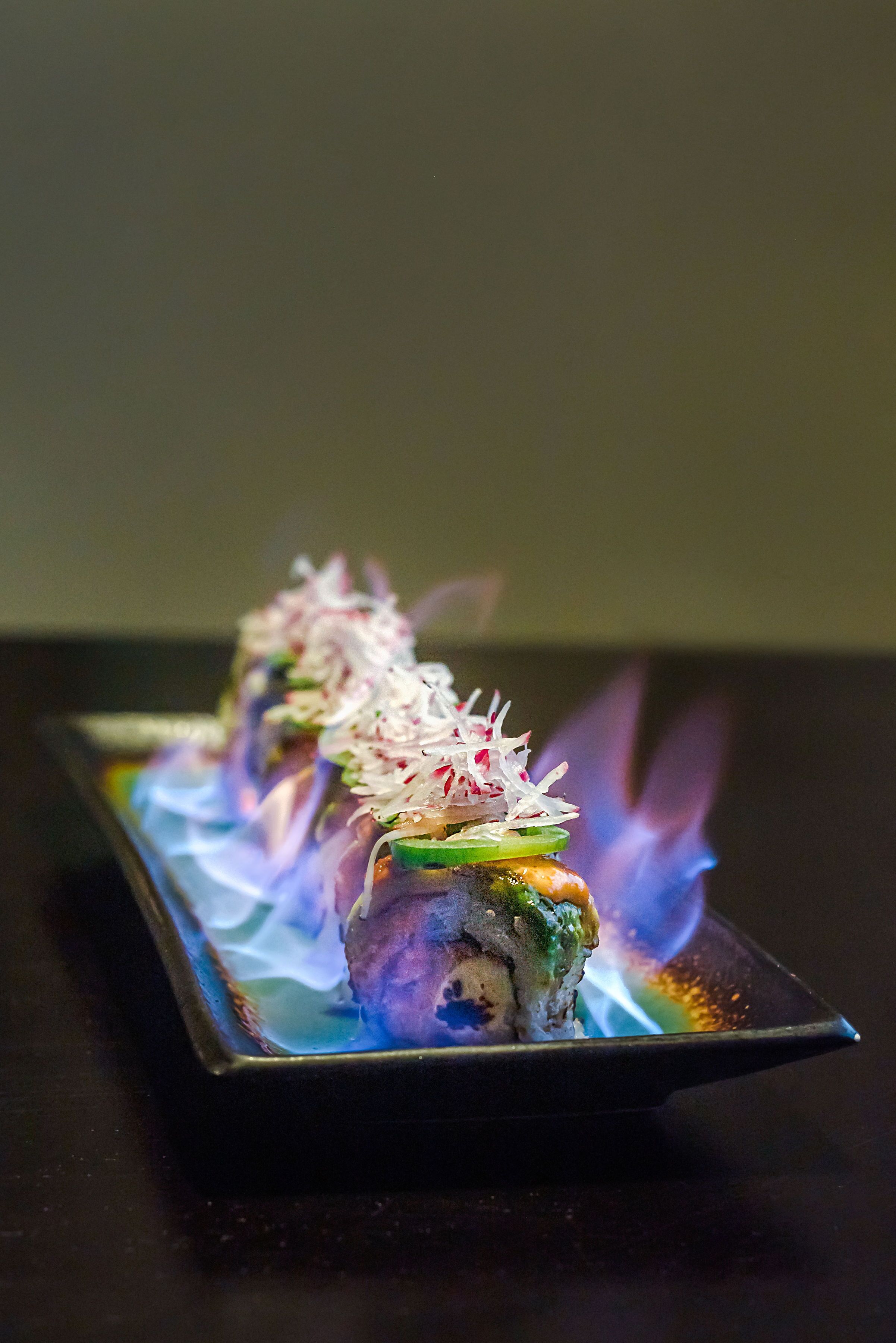 A dish with sushi on a rectangular plate, with a flame effect in the background.