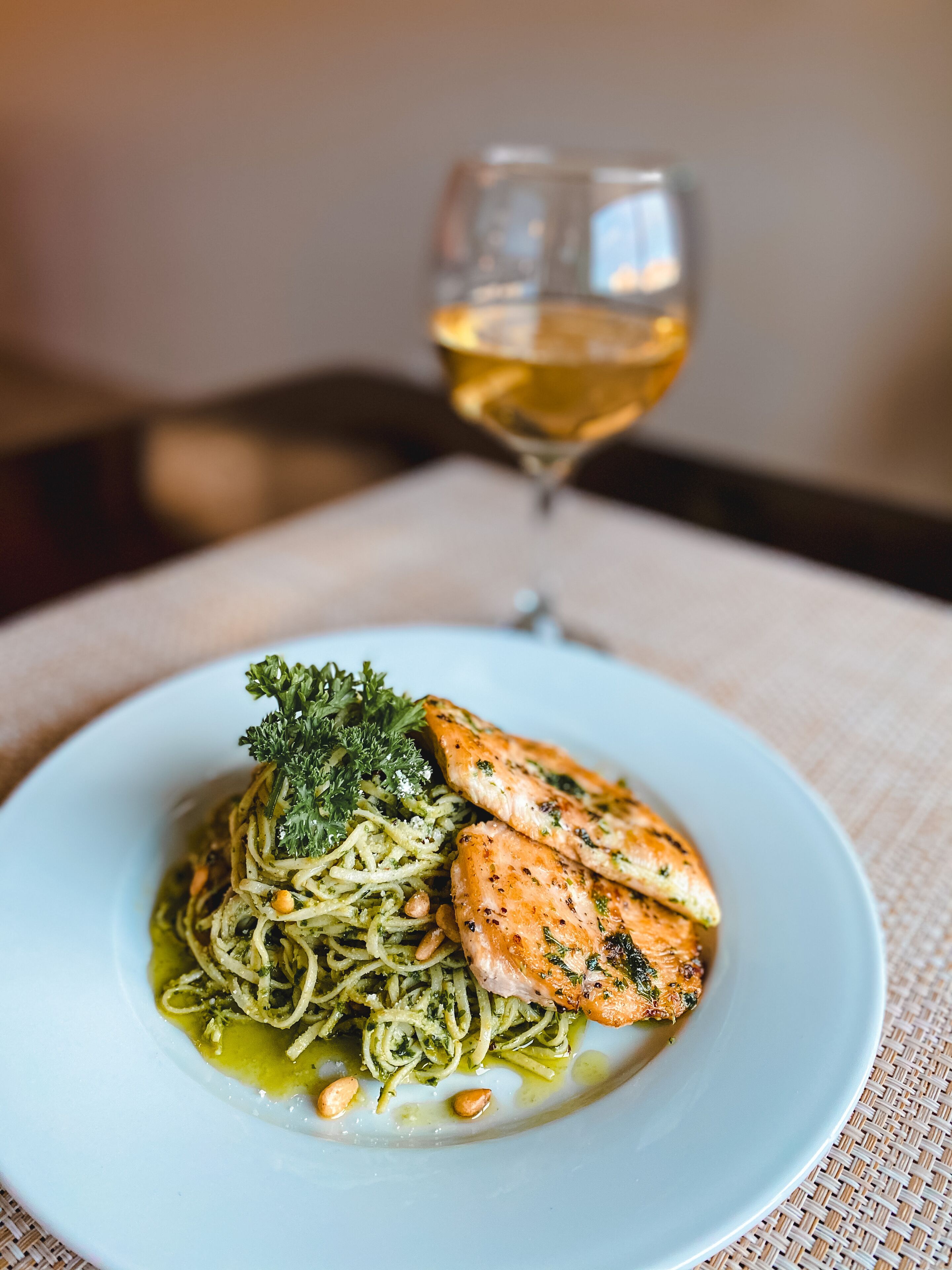 Un plato de comida con una copa de vino blanco sobre una mesa.