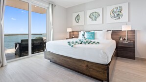 A bedroom with a large bed, a view of the ocean, and three framed shell artworks on the wall. - Sunset Caribe Belize (San Pedro)
