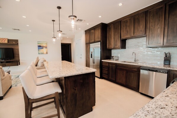 A modern kitchen with dark wood cabinets, stainless steel appliances, and a granite countertop. - Sunset Caribe Belize (San Pedro)