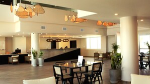 A spacious lobby with a reception desk, seating area, and potted plants. - Sunset Caribe Belize (San Pedro)