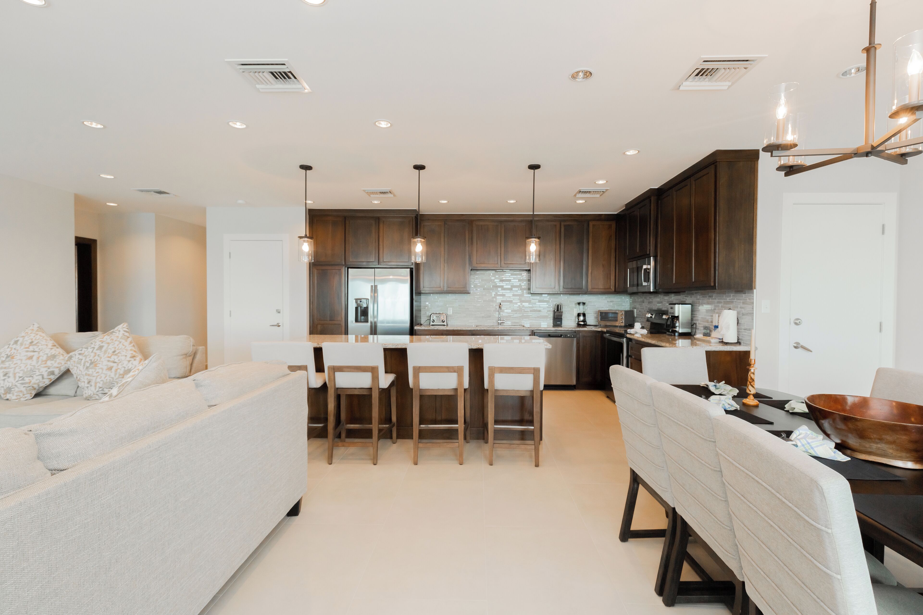 Une cuisine moderne avec des meubles en bois foncé, des appareils électroménagers en acier inoxydable et des luminaires suspendus.