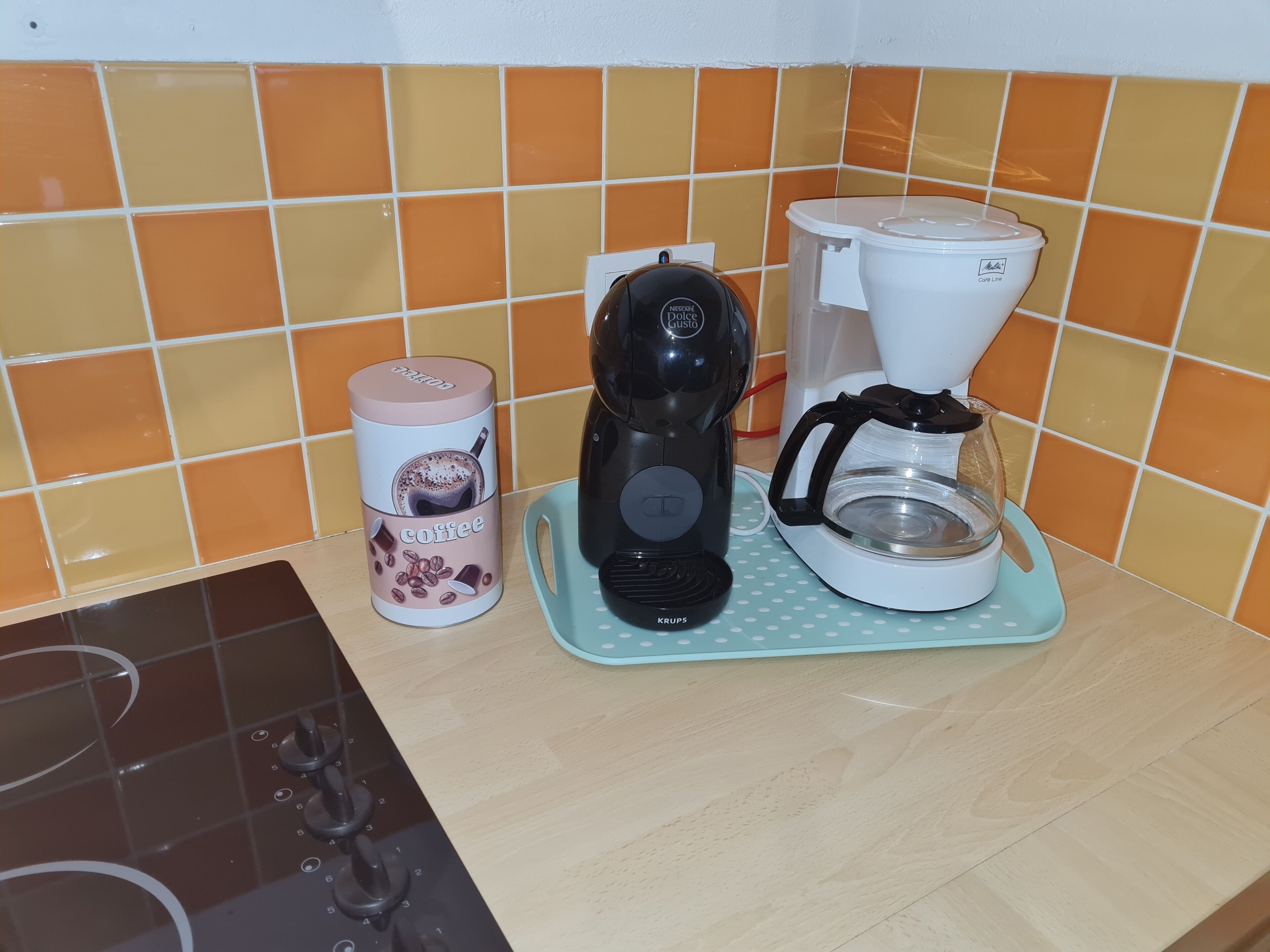 A coffee maker, a coffee pod container, and a coffee pot on a countertop.