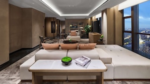 A modern hotel room with a large sofa, a dining area, and a city view. - Hilton Jiaxing (Jiaxing)