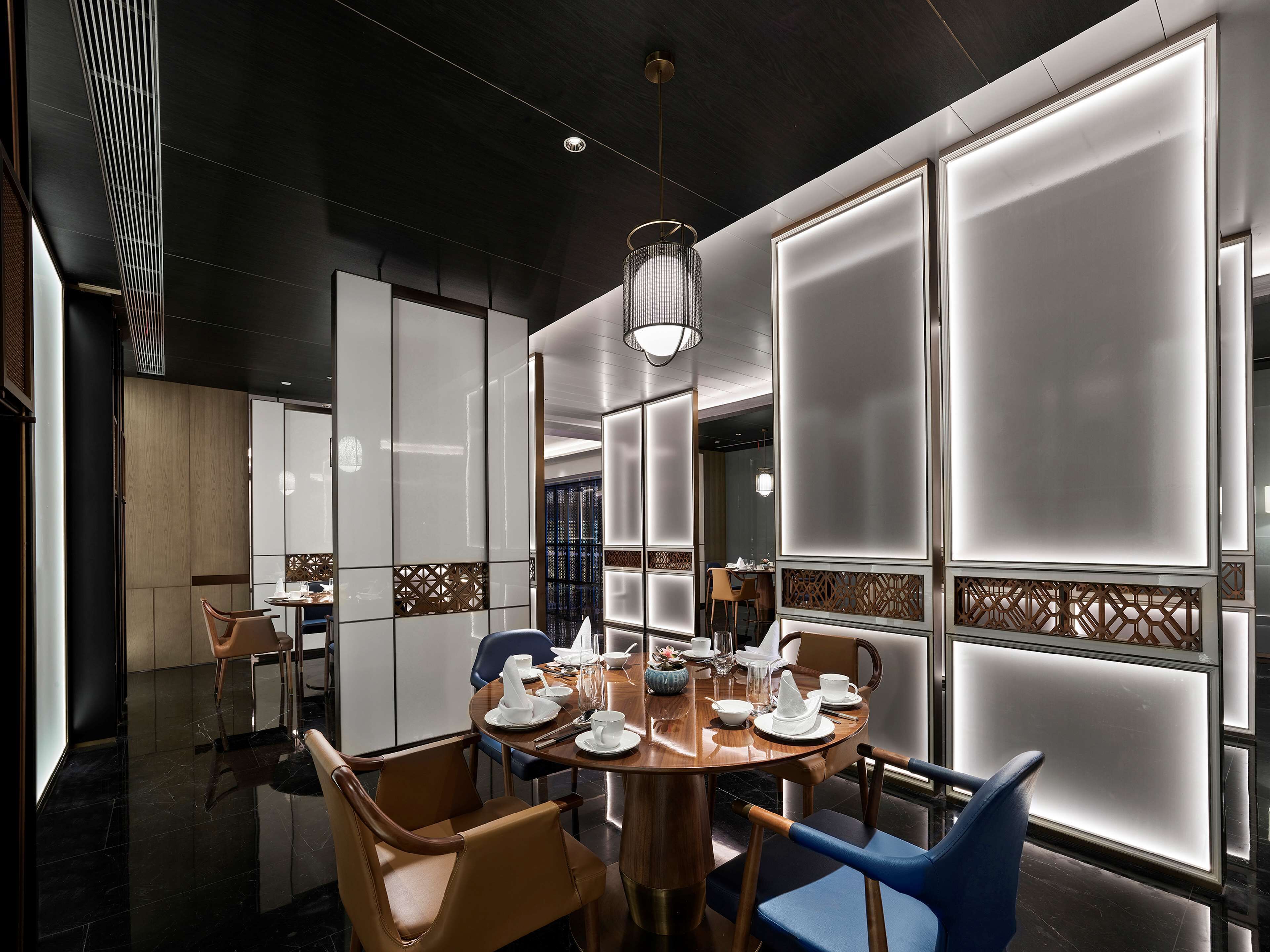 Un comedor moderno con una mesa redonda, sillas y una lámpara decorativa.