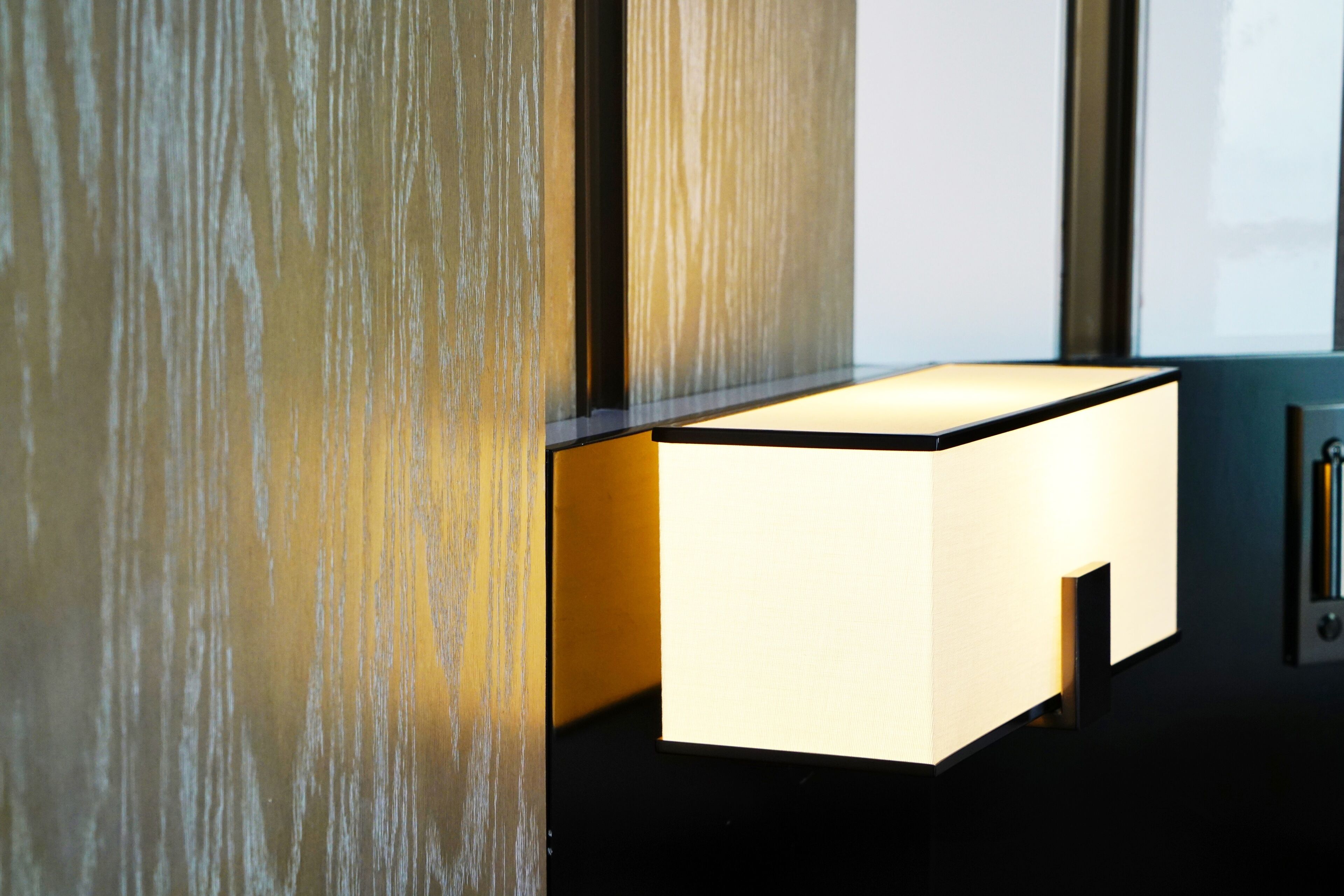 A modern room with a minimalist design, featuring a wall-mounted light fixture and a sleek, dark-colored side table.