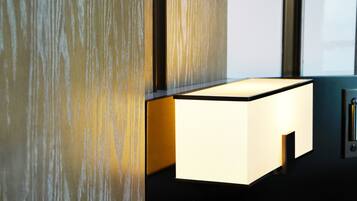 A modern room with a minimalist design, featuring a wall-mounted light fixture and a sleek, dark-colored side table.