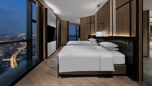 A modern hotel room with a large bed, a TV, and a city view. - Hilton Jiaxing (Jiaxing)