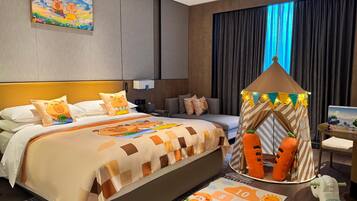 Une chambre d’hôtel comprenant un lit, un espace de jeu aménagé comme une tente, une table de chevet et un téléviseur fixé au mur.