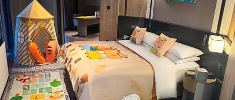 A hotel room with a bed, a play tent, a toy horse, and a children's alphabet mat.