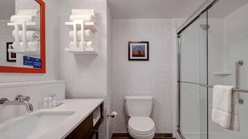 A modern bathroom with a white sink, a toilet, and a glass-enclosed shower.