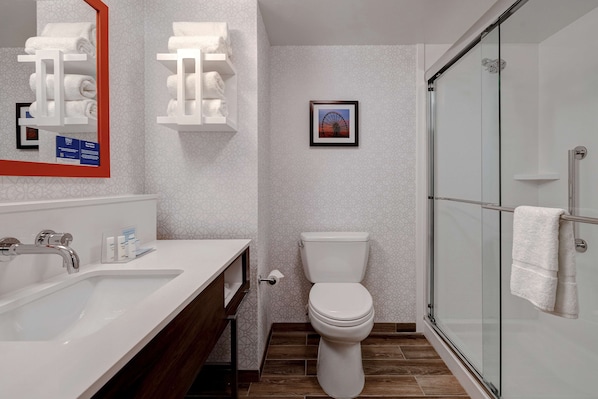 A modern bathroom with a white sink, a toilet, and a glass-enclosed shower.