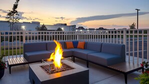 An outdoor seating area with a fire feature and a white fence.