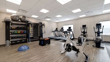 Un gimnasio con equipo de ejercicio, cintas de correr y una estructura para pesas.