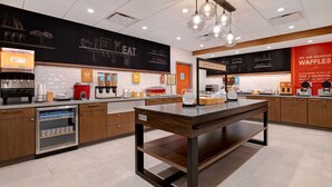 A modern kitchen area with a coffee machine, a refrigerator, and a chalkboard menu.